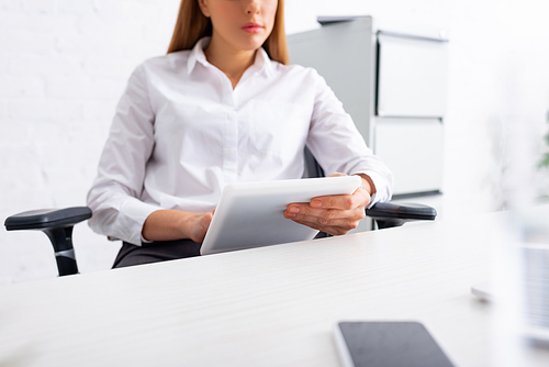 Selective focus of businesswoman using digital tablet at table in office