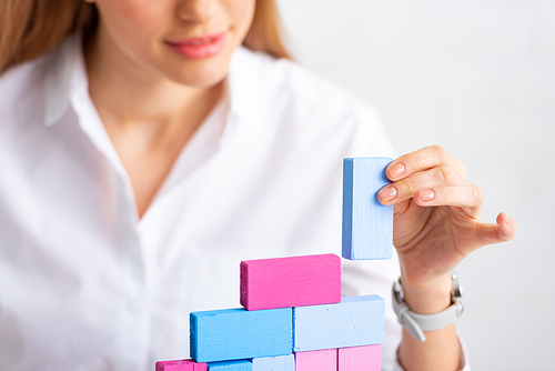 Selective focus of businesswoman stacking colorful building blocks isolated on grey