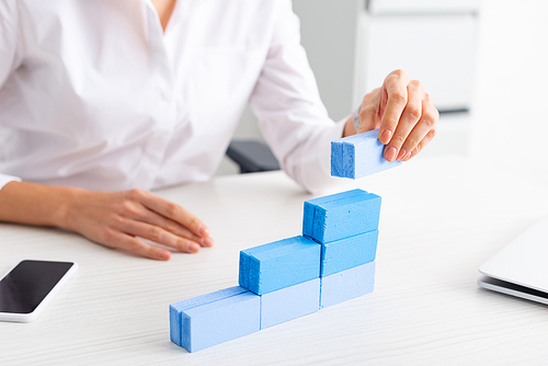 Selective focus of businesswoman stacking blue building blocks on table