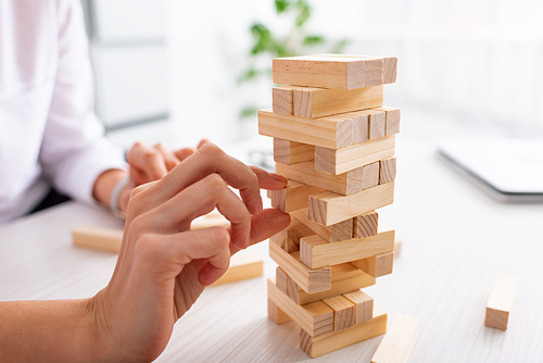 Clopped view of businesswoman playing blocks wood game at table