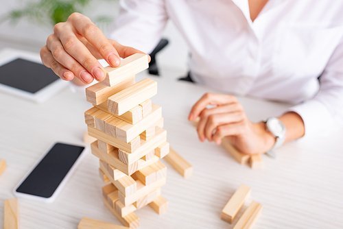 Selective focus of businesswoman playing blocks wood tower game at table