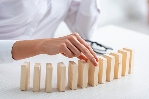 Cropped view of businesswoman playing wooden building blocks at table