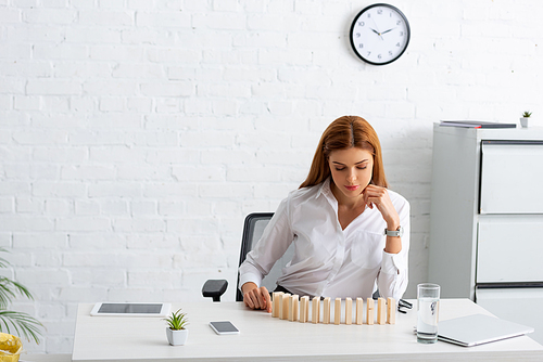 Attractive businesswoman with building blocks and gadgets on table in office