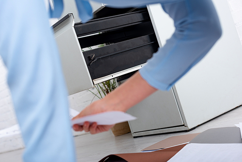 Selective focus of open cabinet driver and businesswoman with documents on floor in office