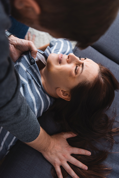 Husband holding shirt of scared wife with bruises near couch