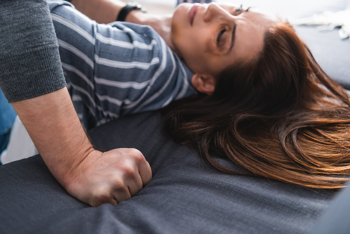 Abuser holding hand in fist near wife with bruises on blurred background