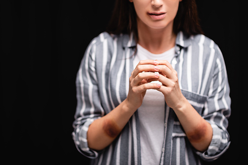 Cropped view of victim of domestic abuse standing isolated on black