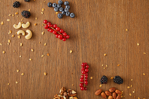 Top view of blueberries, redcurrants, walnuts, almonds, cashews on wooden background