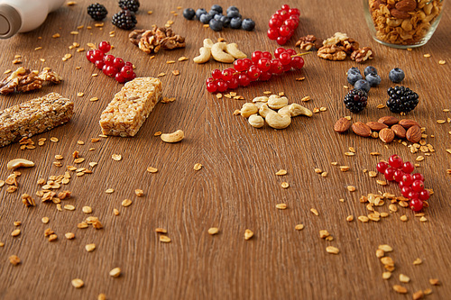 Redcurrants, blueberries, walnuts, almonds, cashews, oat flakes and cereal bars on wooden background