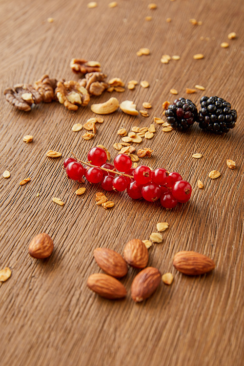 Almonds, cashews, walnuts, redcurrants, blackberries, oat flakes on wooden background