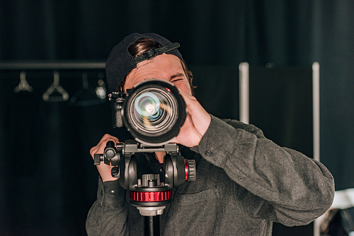 Videographer looking through camera while working in photo studio