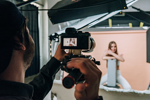 Over shoulder view of videographer filming beautiful model in photo studio