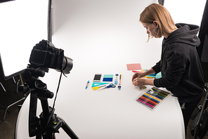 photographer making flat lay with office supplies for commercial photo shooting on white