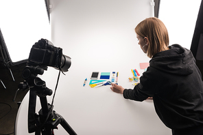 professional photographer making flat lay with office supplies for commercial photo shooting on white