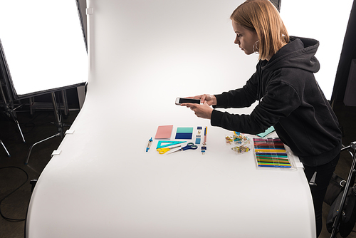 commercial photographer making photos of office supplies on smartphone