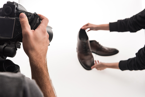 cropped view of commercial photographers making photo shoot of male shoes on white