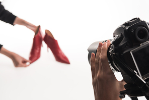 cropped view of photographers making commercial photo shoot of female red heel shoes on white
