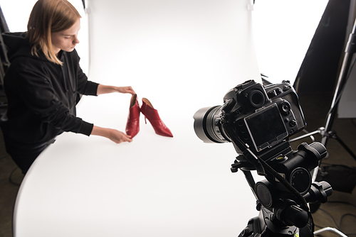 photographer making commercial photo shoot of female red heel shoes on white