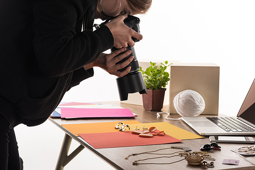 photographer taking photo of composition with flora and accessories for commercial photo shooting with camera and laptop