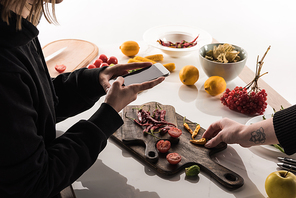 cropped view of two photographers making food composition for commercial photography on smartphone on wooden table