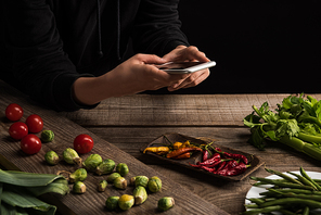 cropped view of photographer making food composition for commercial photography on smartphone on wooden table