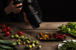 cropped view of female photographer making food composition for commercial photography and taking photo on digital camera