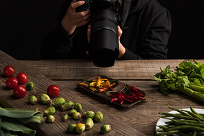 cropped view of female photographer making food composition for commercial photography and taking photo on digital camera on wooden table