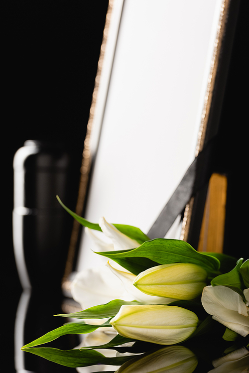 flowers, mirror with black ribbon and urn with ashes, blurred background