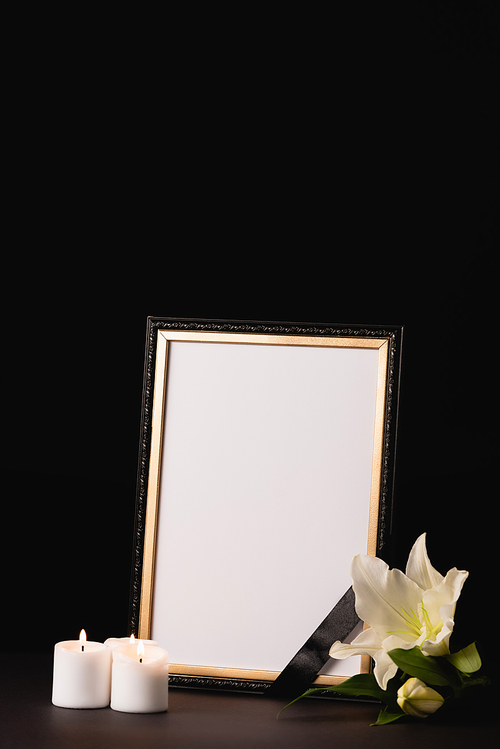 lily, candle and mirror with ribbon on black background, funeral concept