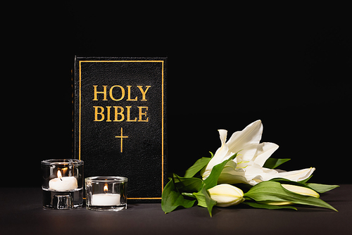 lily, candles and holy bible on black background, funeral concept