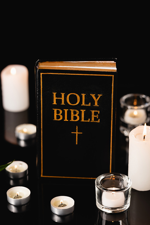 candles and holy bible on black background, funeral concept