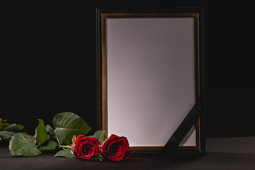 two red roses and mirror with ribbon on black background, funeral concept