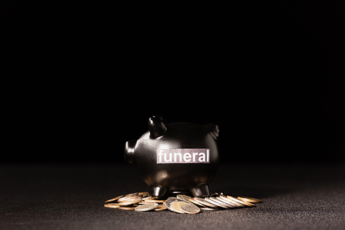 piggy bank with coins on black background, funeral concept