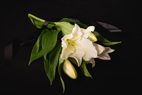 lily bouquet and ribbon on black background, funeral concept