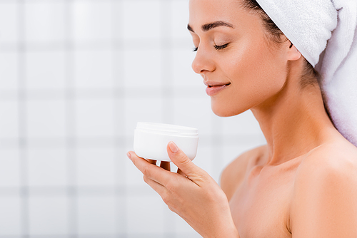 pleased woman enjoying flavor of cosmetic cream with closed eyes in bathroom