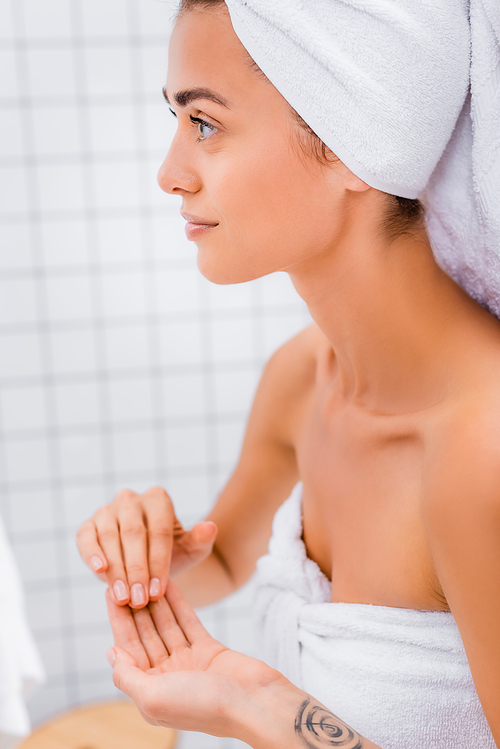 young woman with perfect skin and white terry towel on head in bathroom