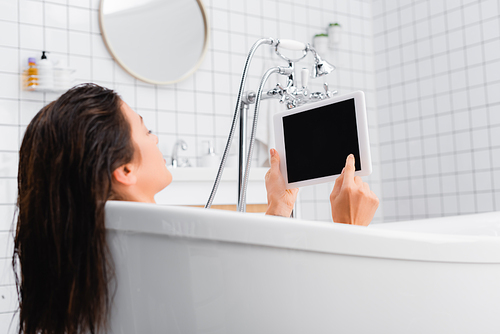 young woman taking bath and using digital tablet