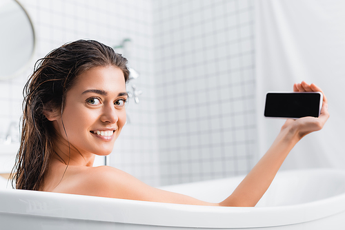 happy young woman taking selfie while taking bath and smiling at camera