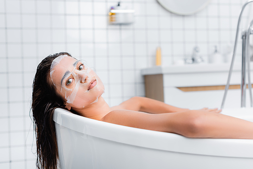 young woman in face mask relaxing in bathtub and 