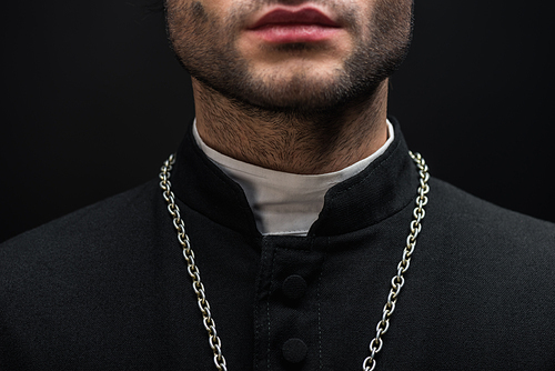 cropped view of catholic priest in black cassock with silver necklace isolated on black