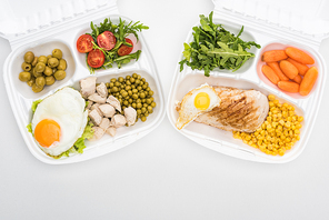 top view of  packages with arugula, vegetables, meat, fried eggs and salad on white background