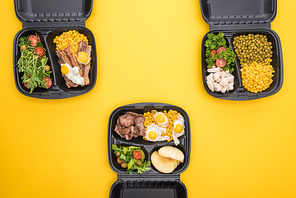 top view of  packages with apples, vegetables, meat, fried eggs and salads isolated on yellow