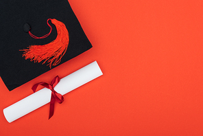 Top view of academic cap and diploma isolated on red
