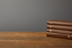 Four brown books on textured wooden surface on grey