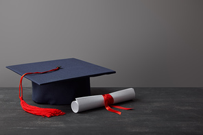 Brown books, globe and diploma with red ribbon on grey