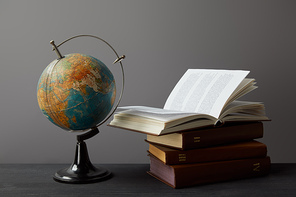 Brown books, globe and diploma with red ribbon on grey