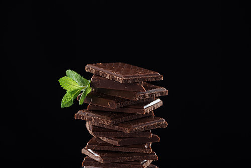 Dark pieces of chocolate with fresh mint, isolated on black