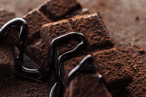 Selective focus of chocolate bar with melted chocolate and cocoa powder