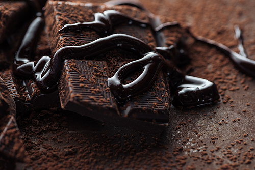 Close up view of chocolate bar with melted chocolate and cocoa powder