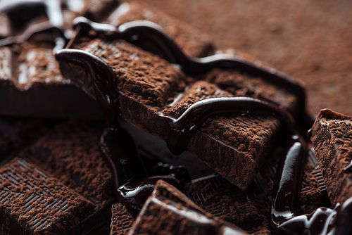 Close up view of pieces of dark chocolate bar with liquid chocolate